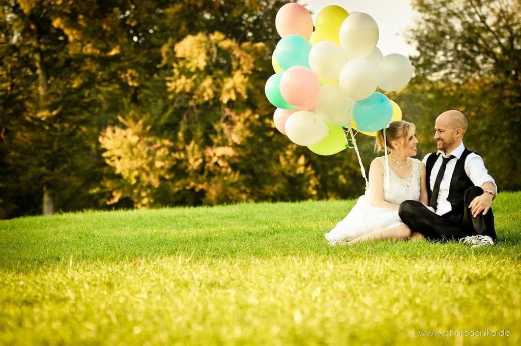 Brautpaar sitzt in der Wiese mit Luftballons