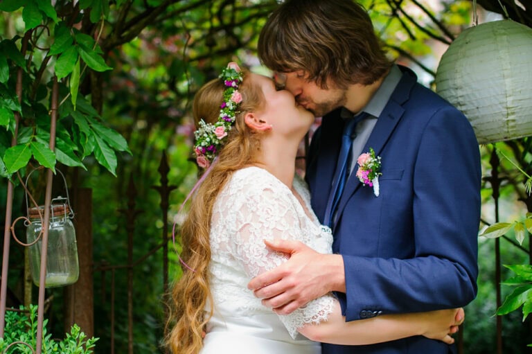 Hochzeitspaar in inniger Umarmung während der Trauung im Grünen, umgeben von Natur und Dekorationen, bei eleganter Hochzeitsfotografie in München und Umgebung.