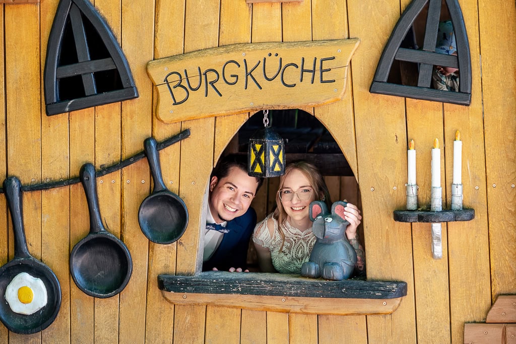Ein junges Brautpaar freut sich im Kuchenhäuschen auf einer Hochzeit in München, umgeben von rustikaler Holzausstattung, Kerzen und Dekorationen.